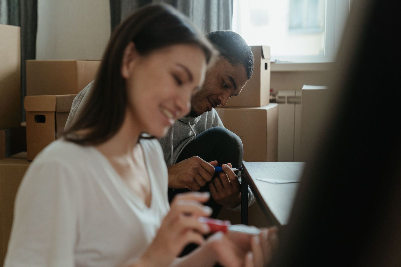 Paar baut in der neuen Wohnung zwischen Umzugskartons ein Möbelstück zusammen